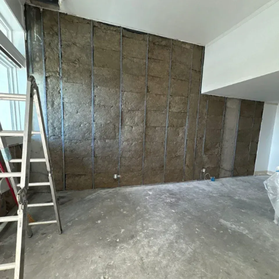 Renovation room with a ladder beside an unfinished wall covered in brown insulation panels.