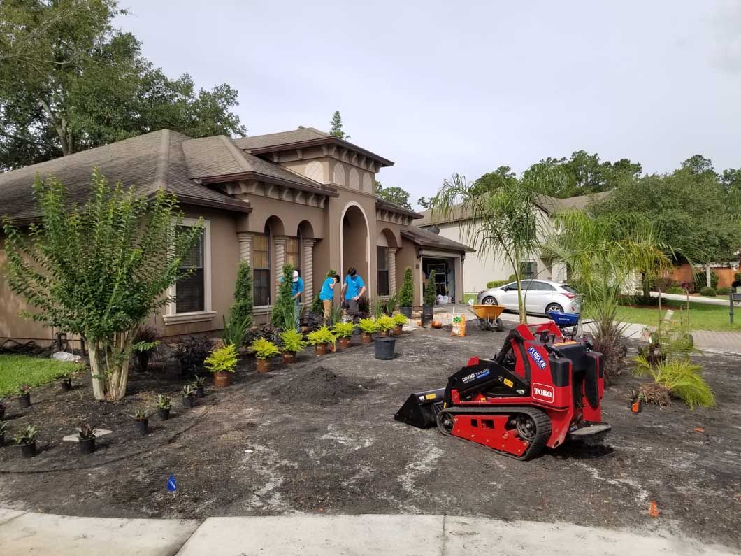 House under construction with a red mini excavator in a muddy yard