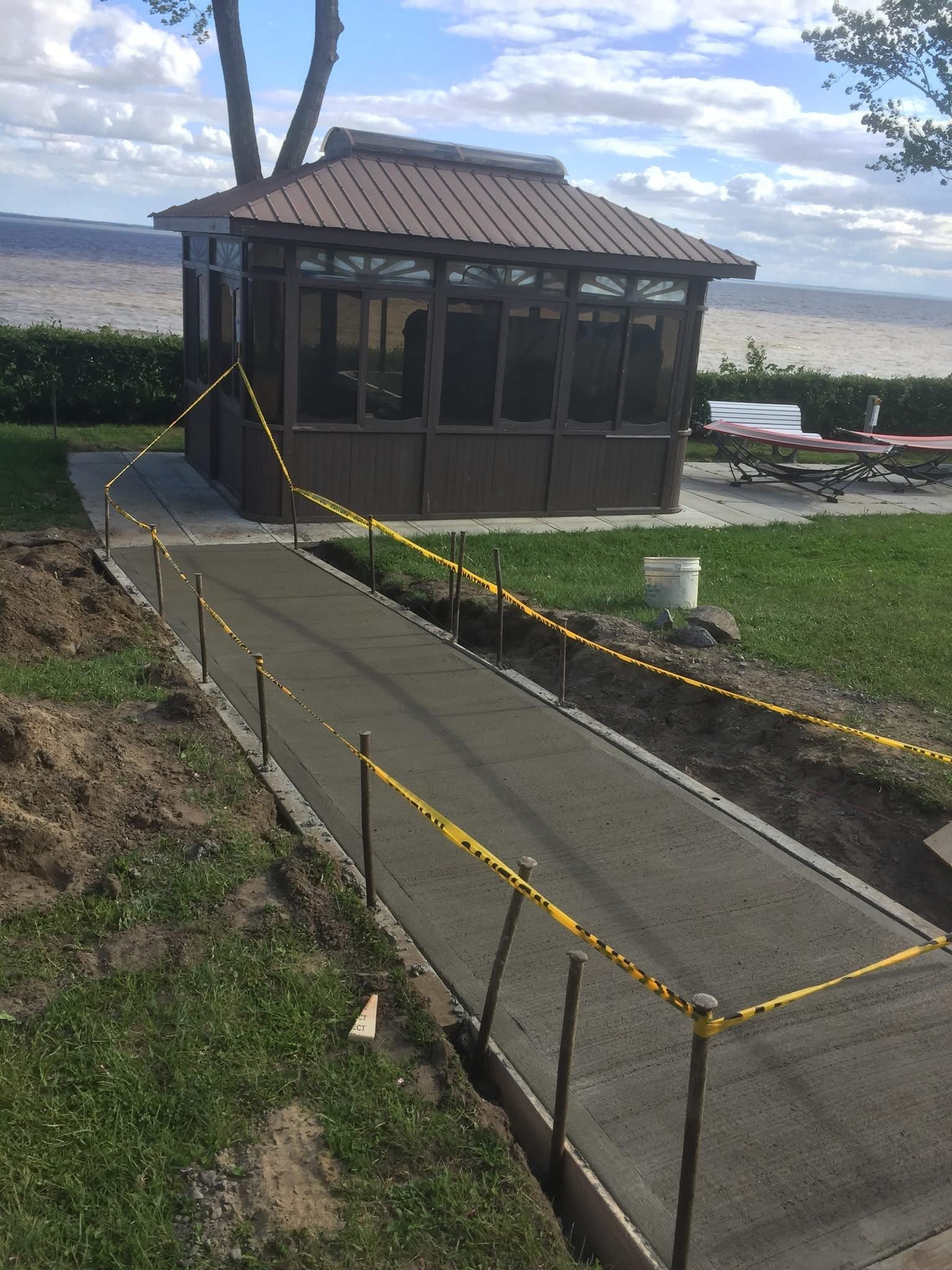 Un belvédère est en cours de construction dans une cour arrière à côté d'une passerelle en béton.