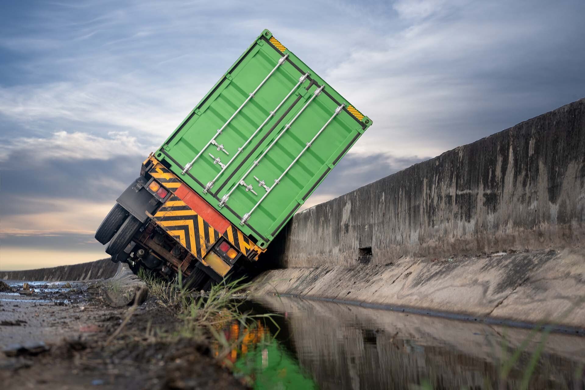 Truck Accident - Detroit, MI - Frederic M Rosen, PC Attorney At Law A green semi-truck overturned, leaning into a ditch, on a cloudy day.