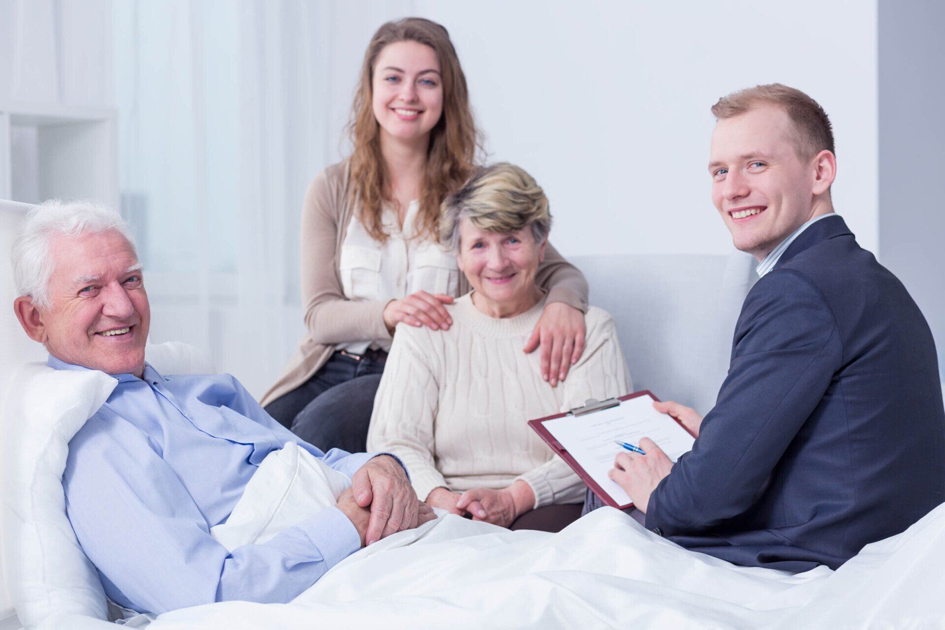 There's Nothing To Worry About - Detroit, MI - Frederic M Rosen, PC Attorney At Law Elderly man in bed with family, and a man with a clipboard. Everyone smiling.
