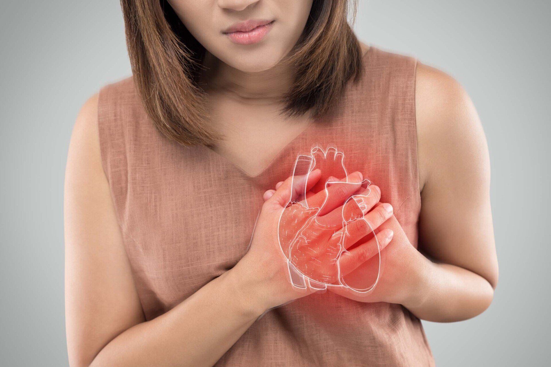 Woman clutching chest in apparent pain, outlined heart glows red.