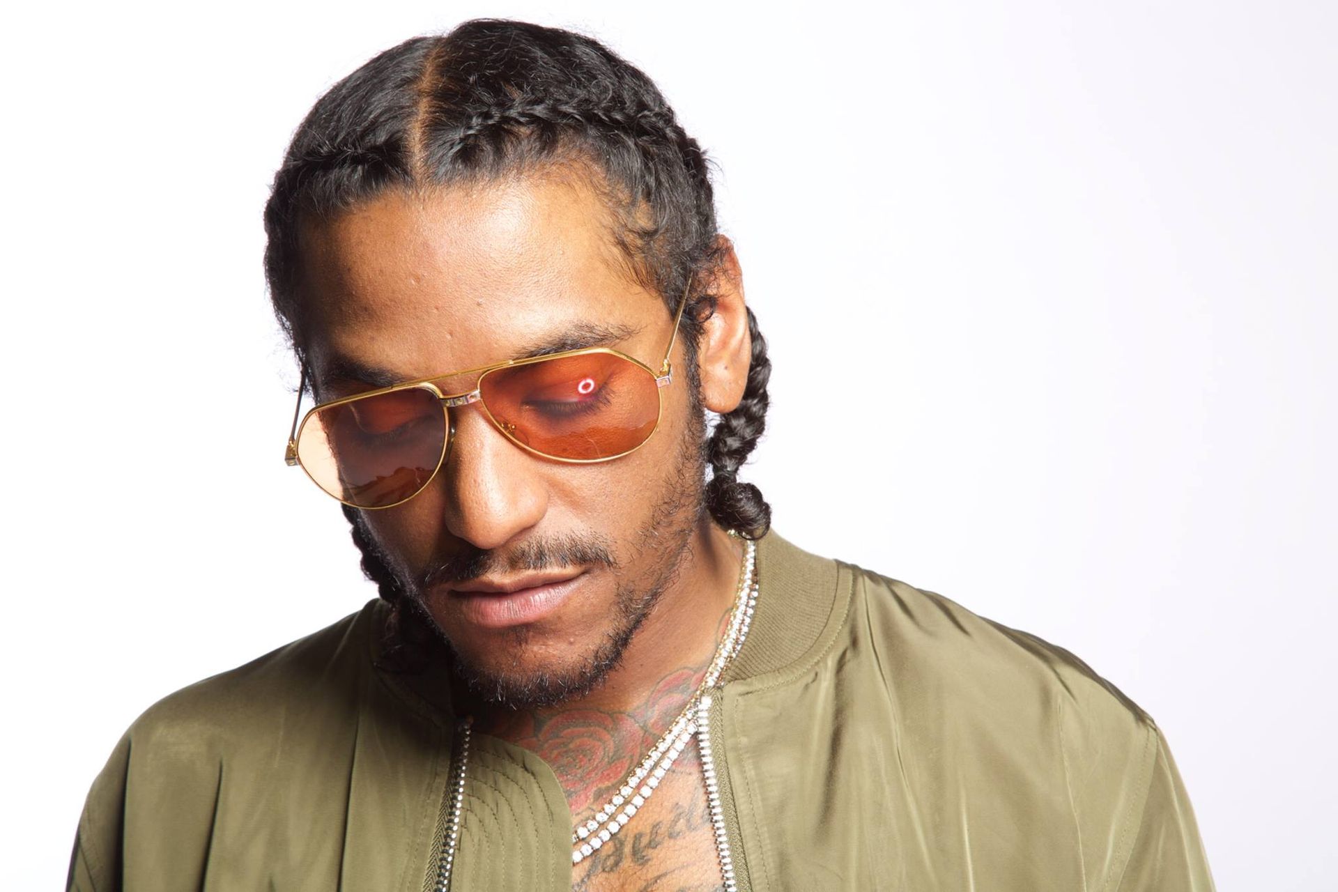 Singer, Floyd wearing sunglasses and a green jacket is looking down.