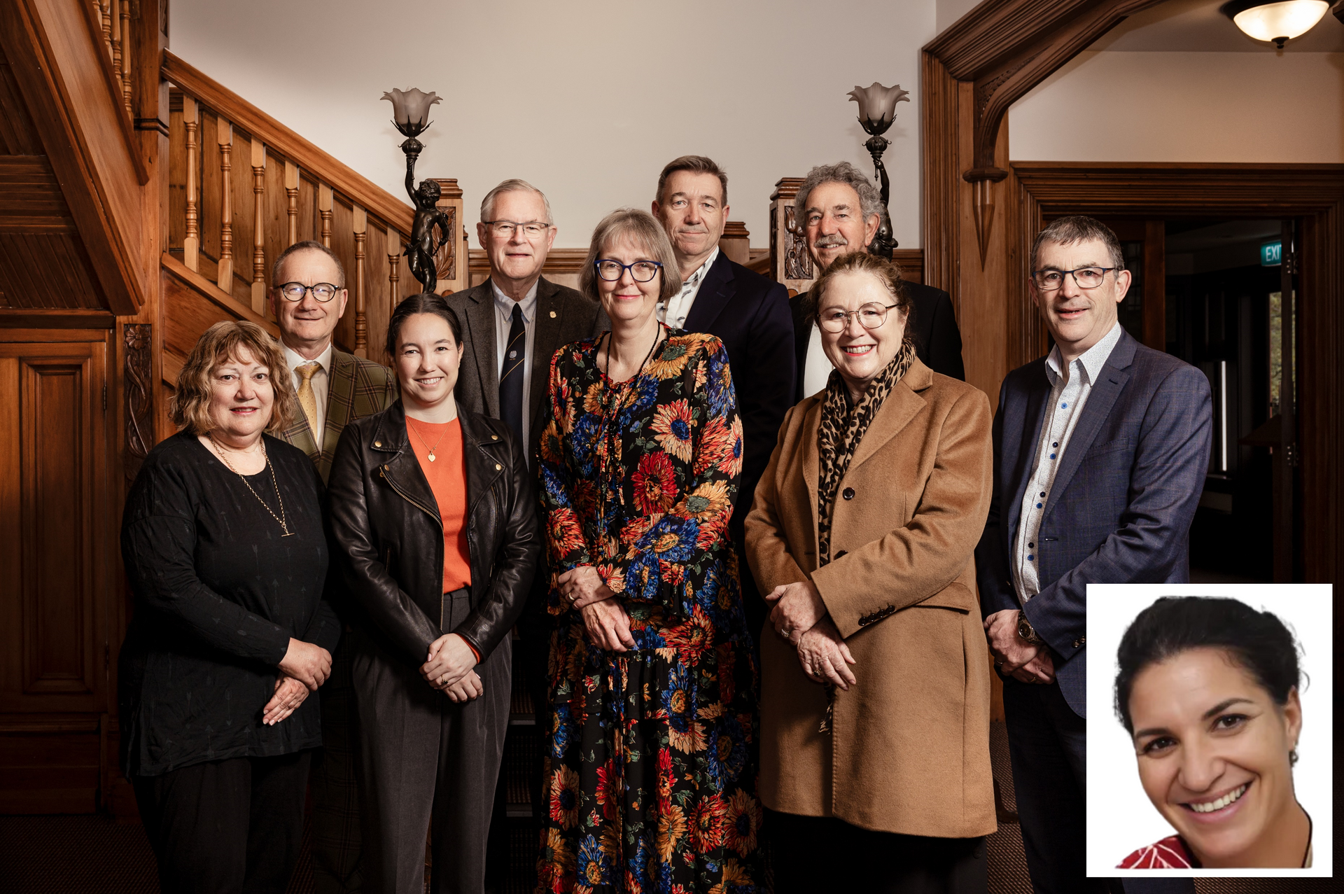 A group of people posing for a picture in front of a wooden staircase
