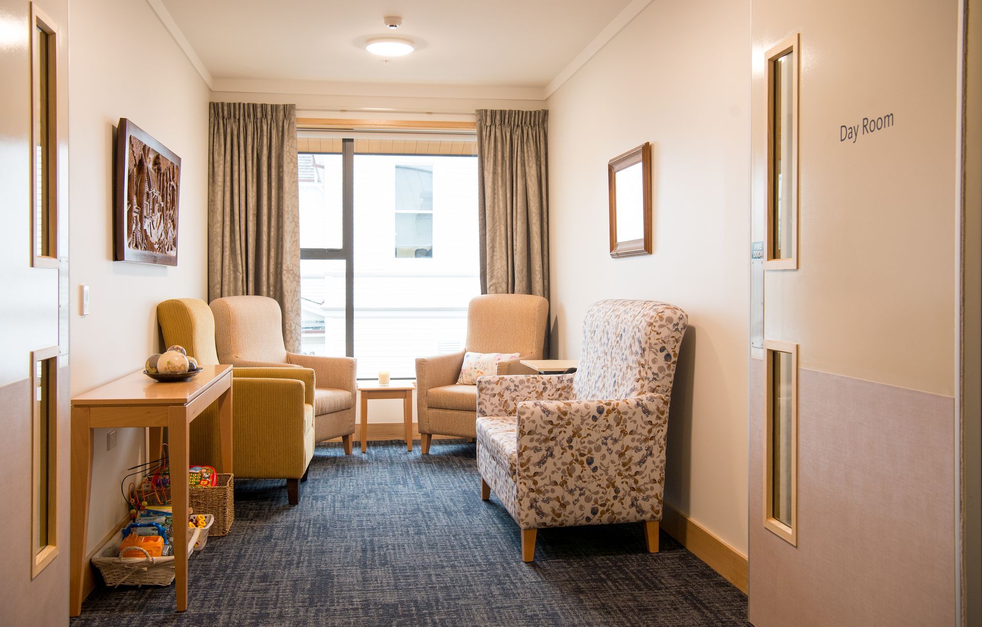Waiting room with armchairs, side tables, window, and two doors.
