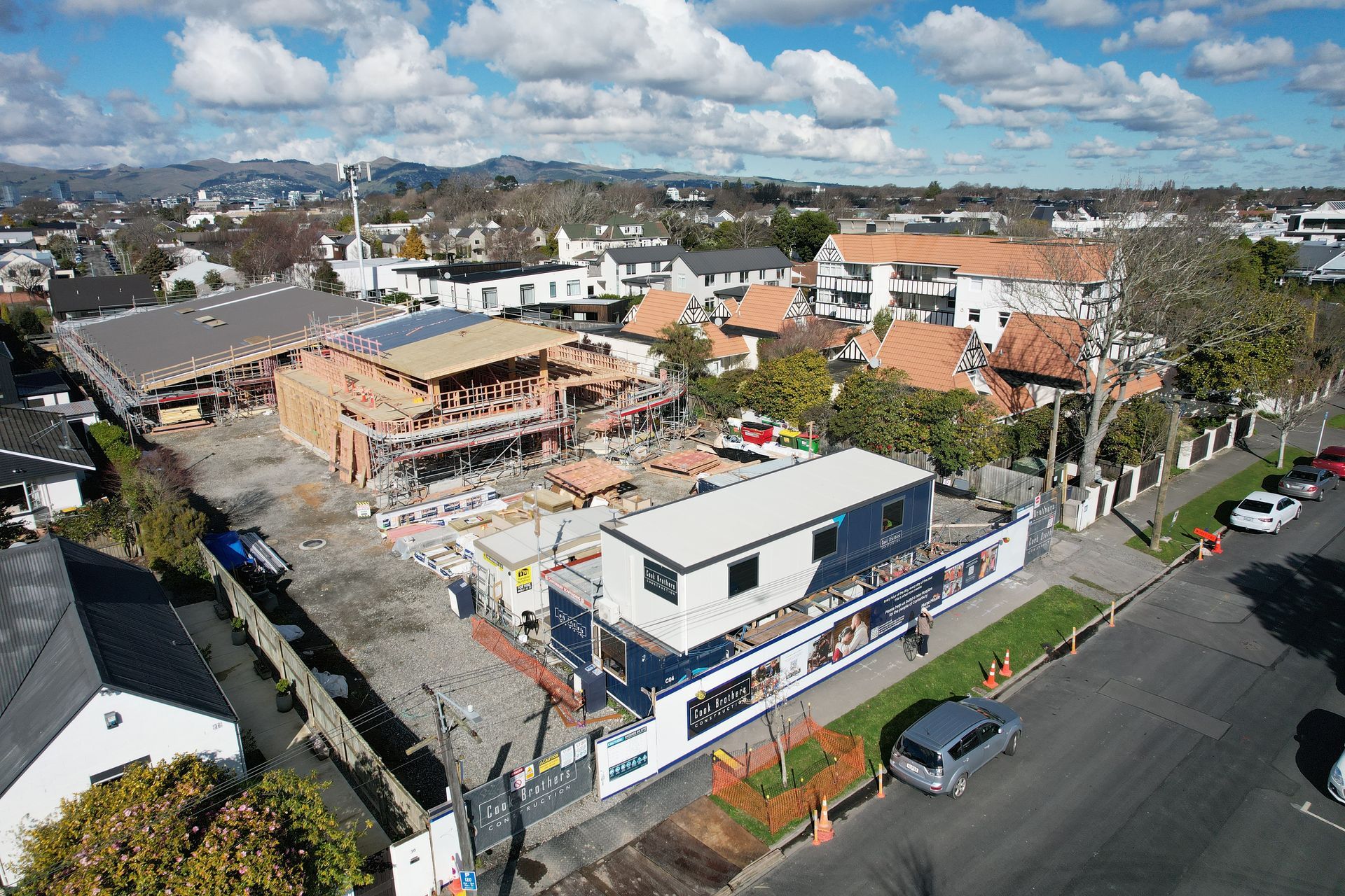 Aerial view of a construction site with buildings in various stages of completion. Blue sky, residential area.