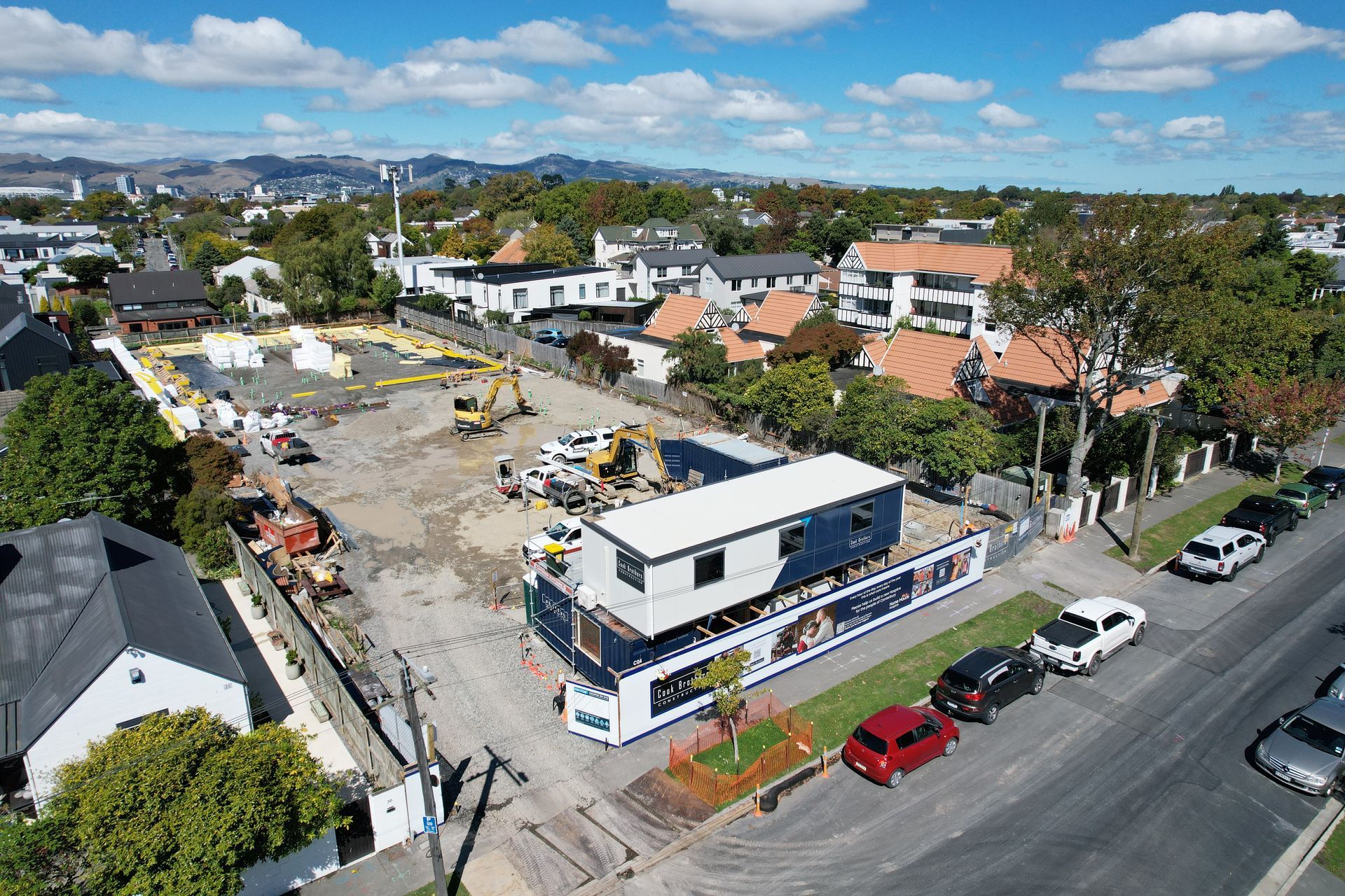Aerial view of a construction site with buildings, vehicles, and a two-story modular building.