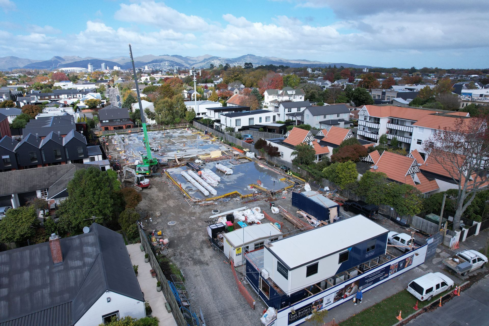 Construction site aerial view with a crane, buildings, and vehicles.
