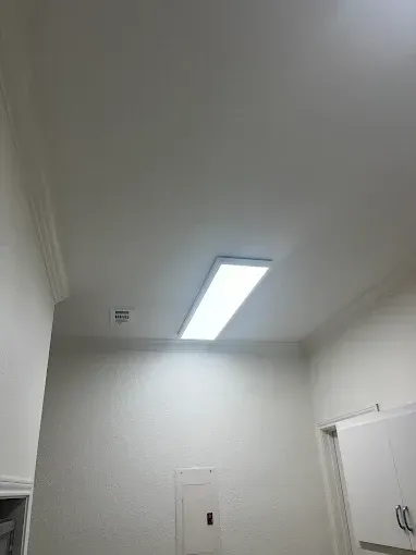 White room with a bright rectangular ceiling light and a closed door.