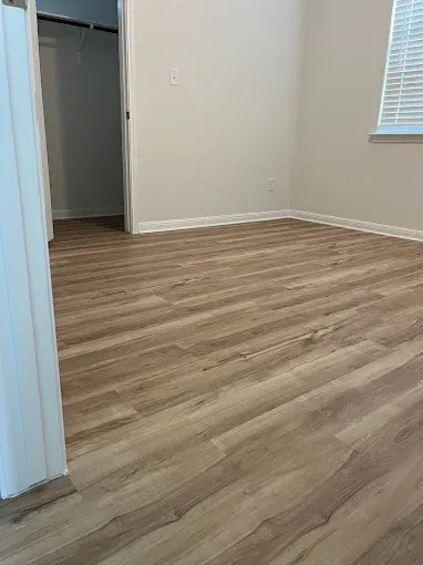 Empty room with wood-look flooring, white walls, and a small window.