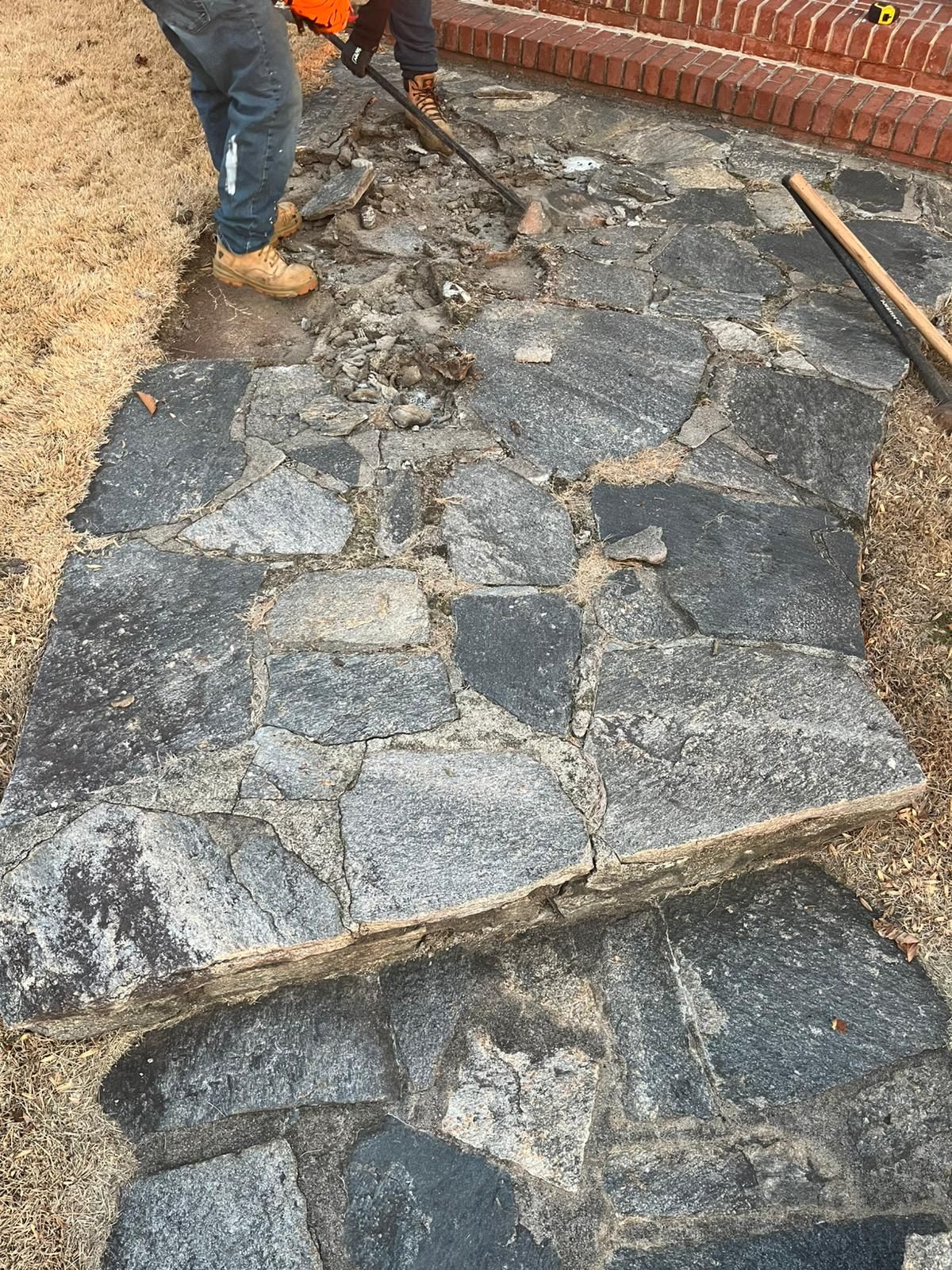 A man is cleaning a stone walkway with a vacuum cleaner.