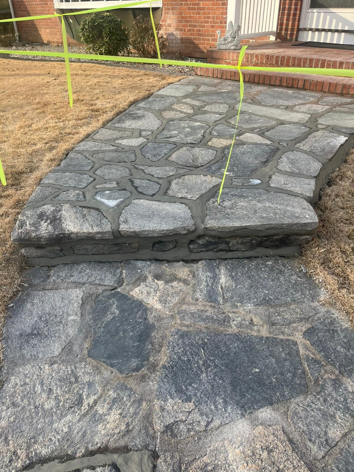 A stone walkway is being built in front of a brick house.