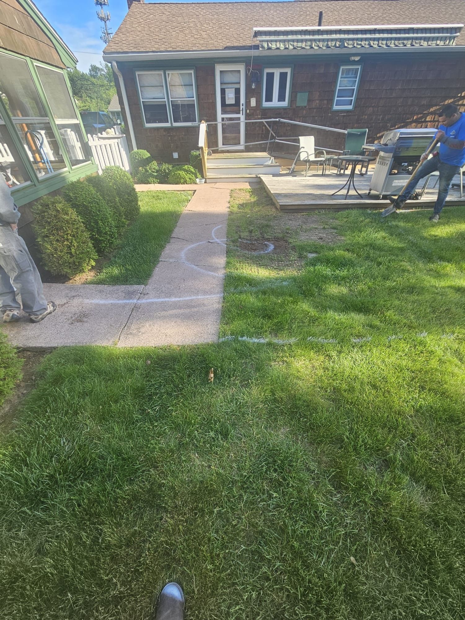 A person is standing in the grass in front of a house.