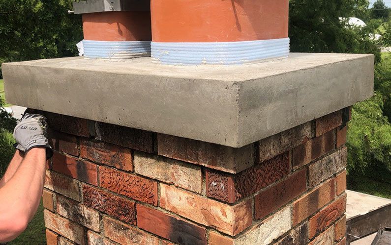 A man is fixing a brick chimney on a roof.