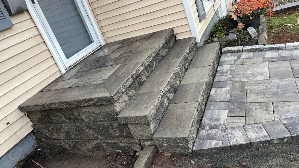 A stone porch with steps and a brick walkway next to a house.