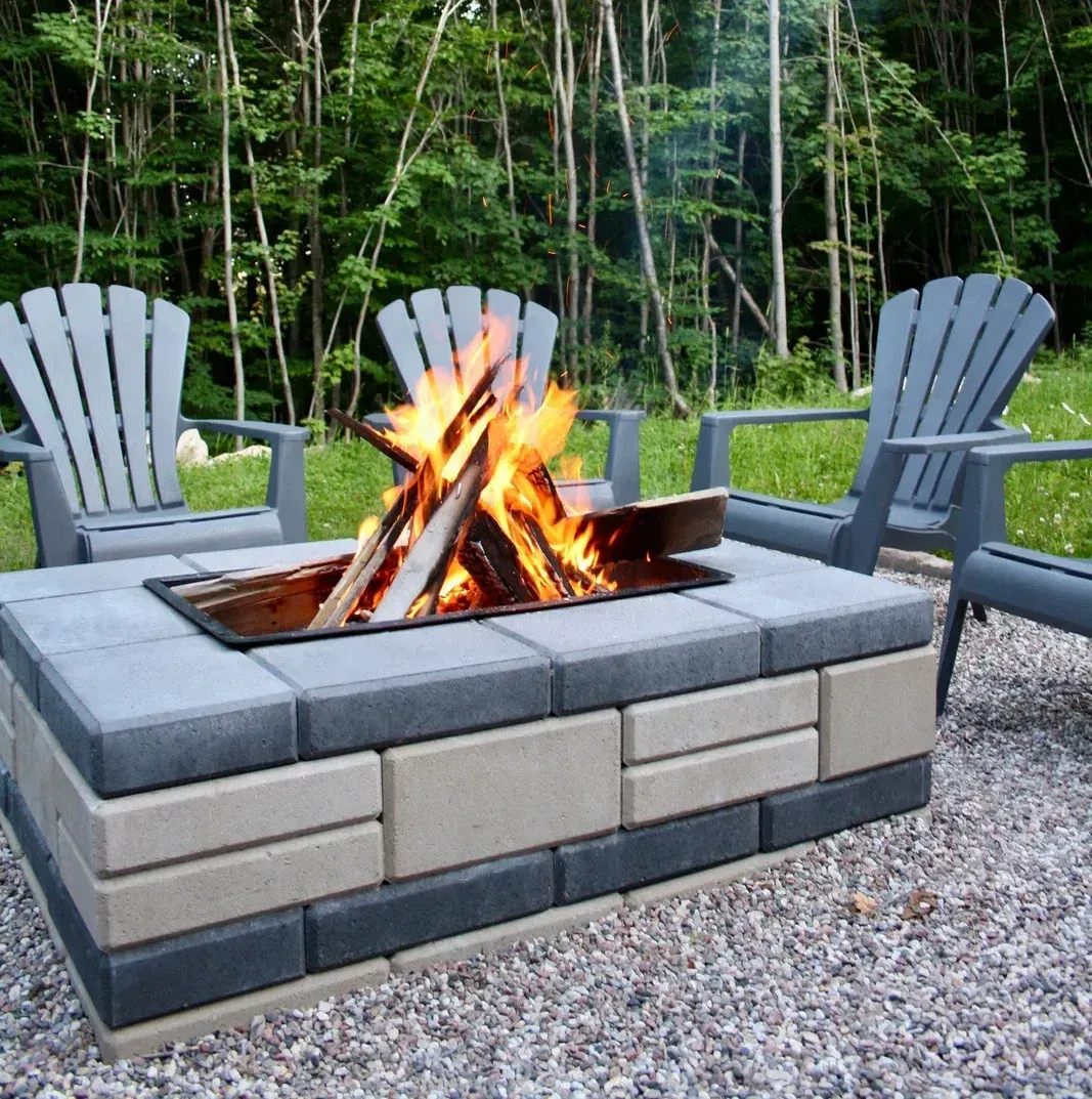 A fire pit with two chairs in the background