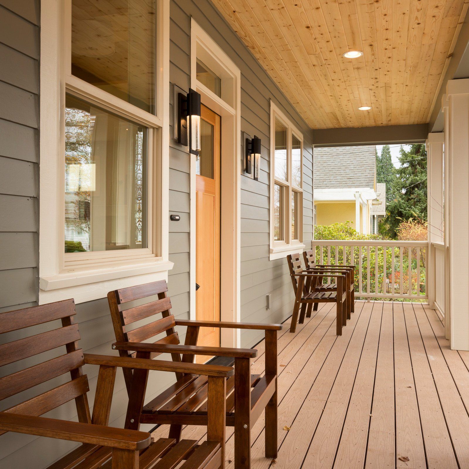 A porch with wooden benches and chairs on it