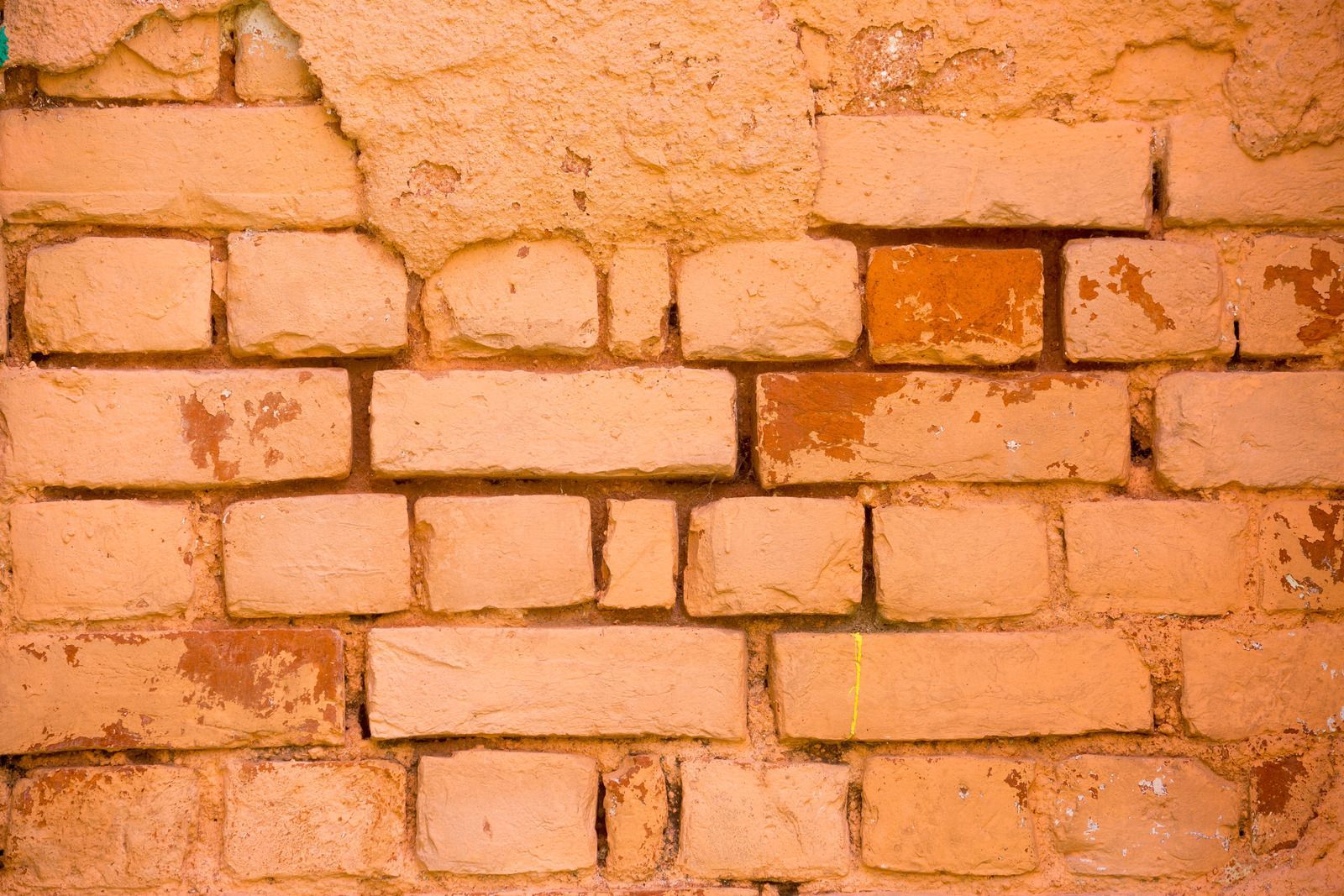 A close up of a brick wall with peeling paint.