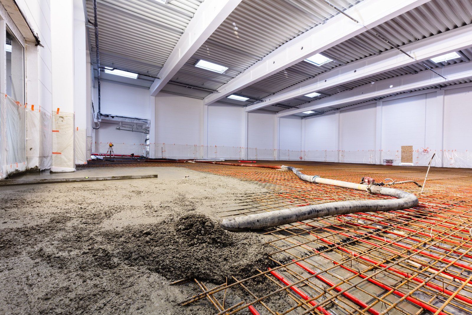 A large warehouse under construction with concrete being poured on the floor.