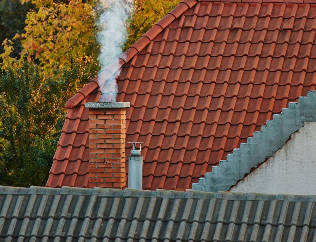 Smoke is coming out of a chimney on the roof of a house