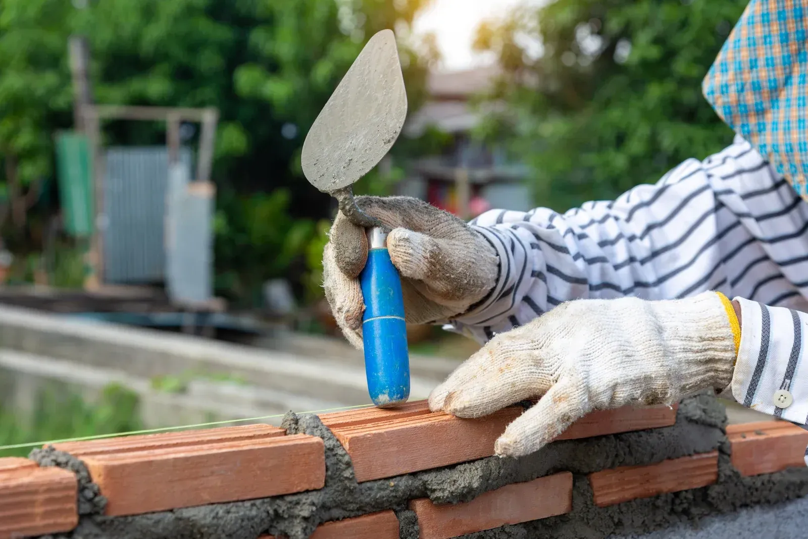 A man is using a trowel to build a brick wall.