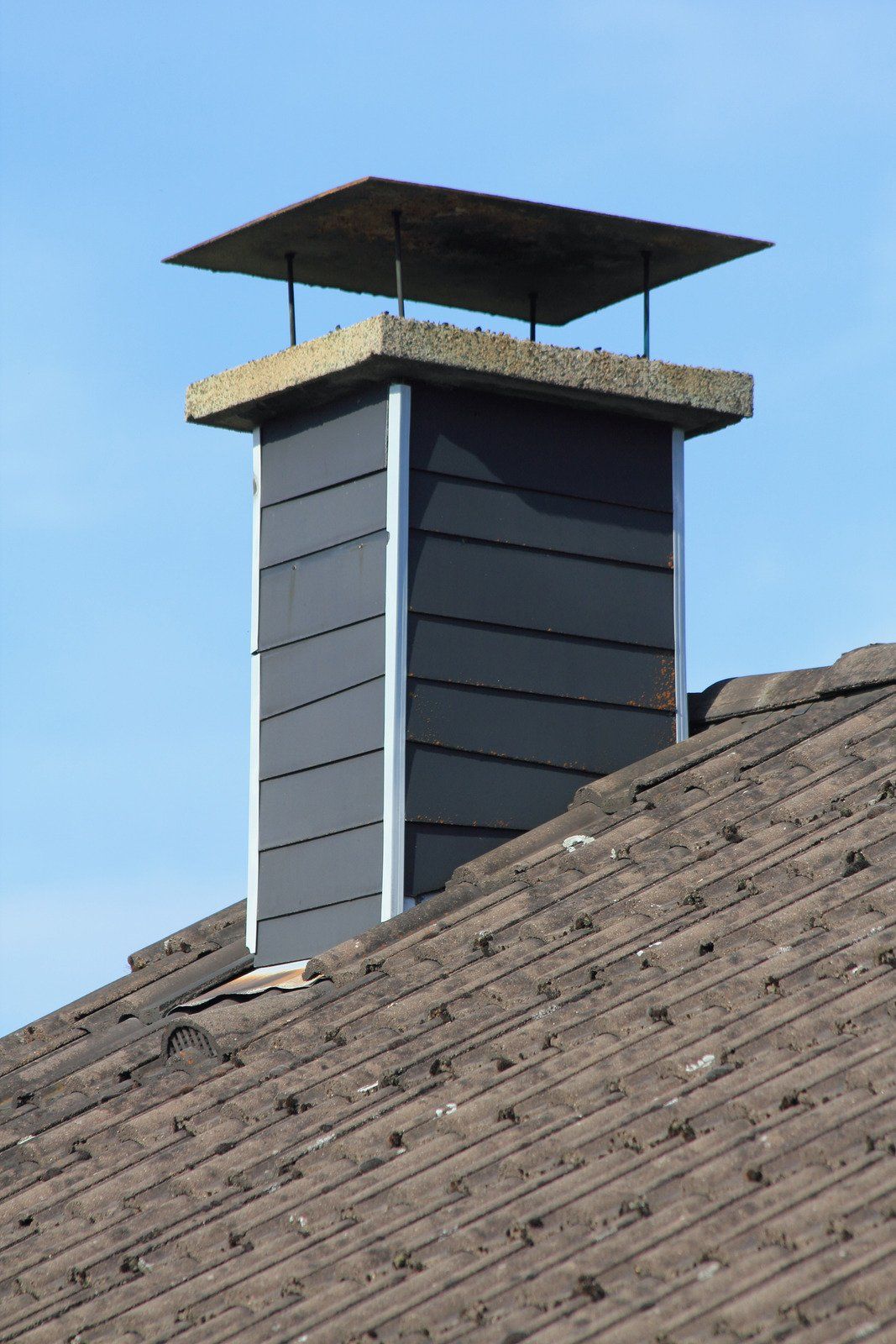 A chimney on top of a roof with a blue sky in the background