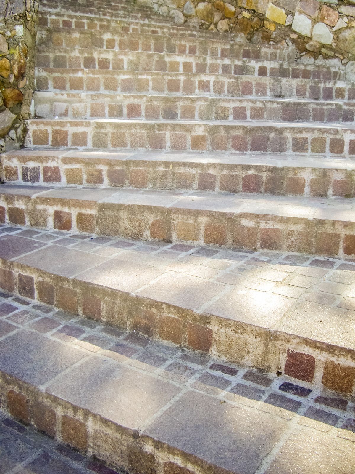 A set of brick stairs leading up to a stone wall.