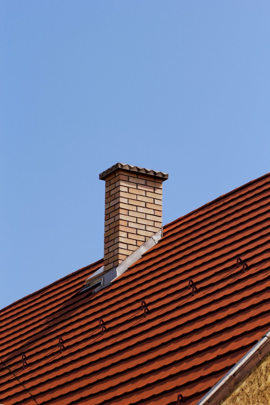 A brick chimney is sitting on top of a red tiled roof.