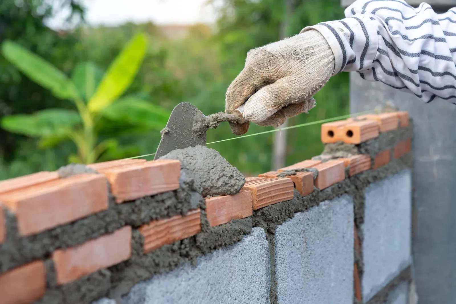 A person is laying bricks on a wall with a trowel.