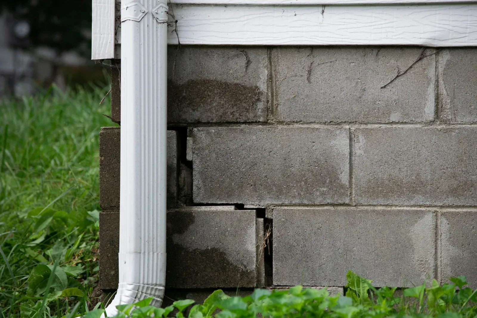 A brick wall with a hole in it and a drain pipe.