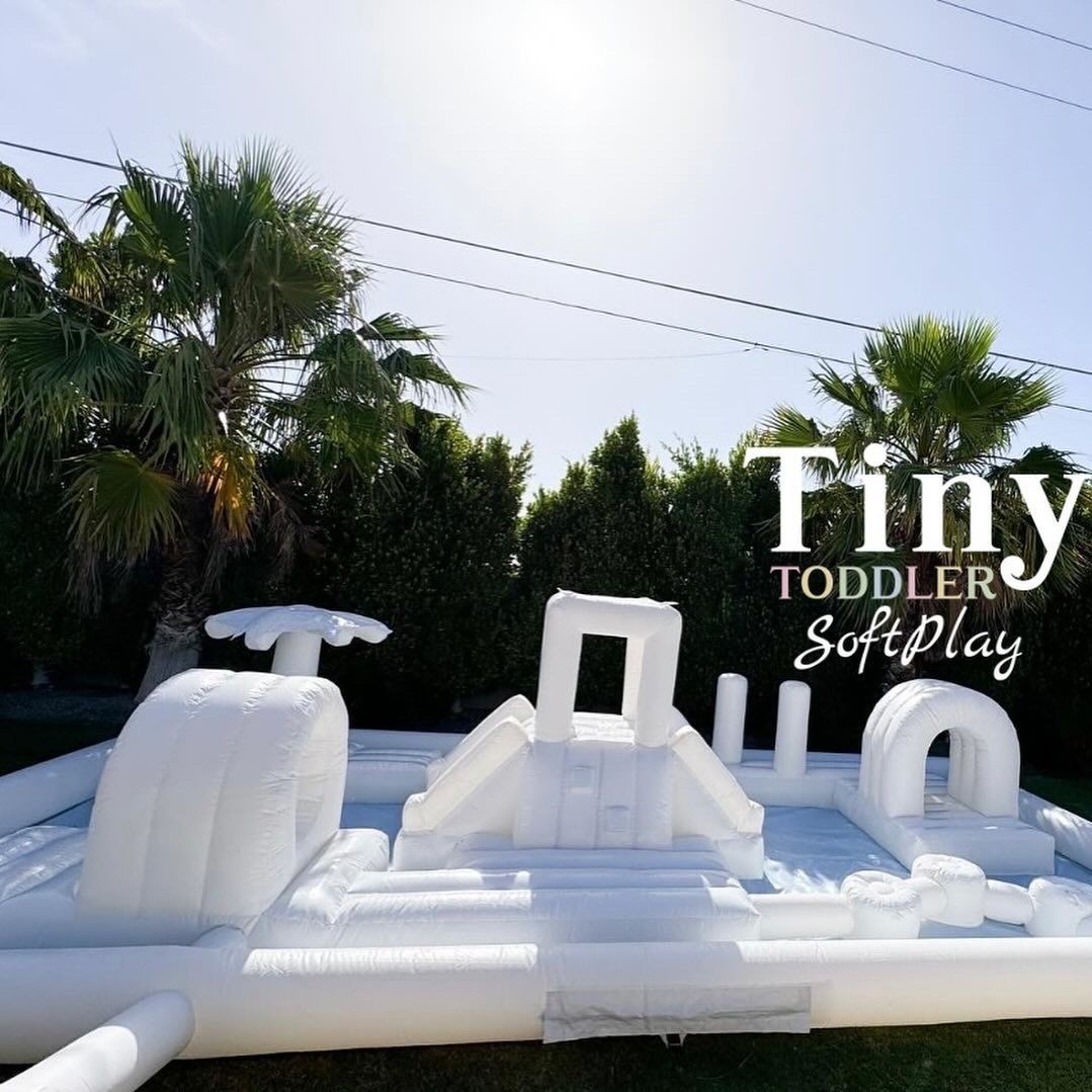 White inflatable toddler splash pad in a sunny backyard with palm trees