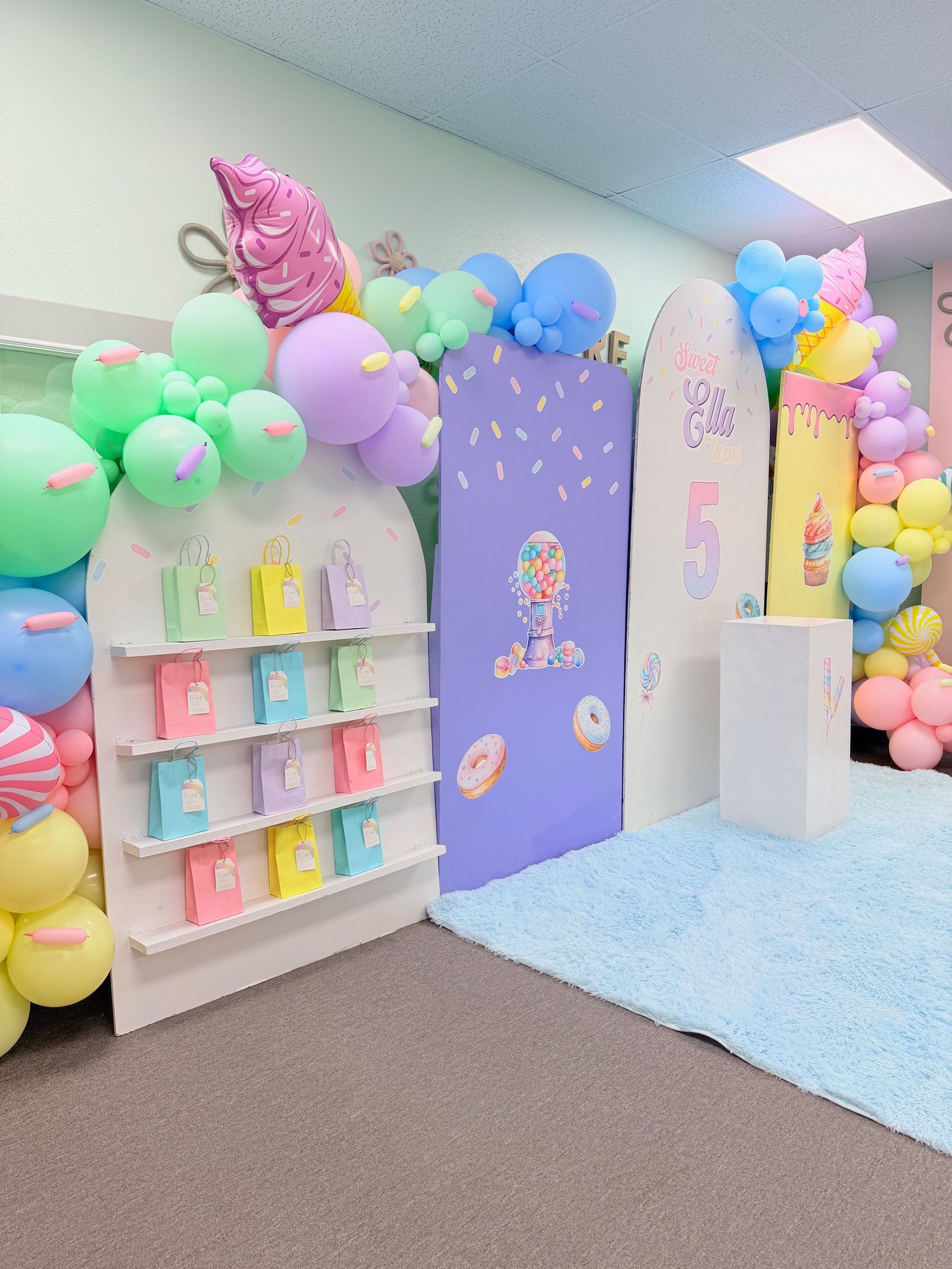 Colorful balloon-decorated party room with pastel shelves, a purple panel, and a blue carpeted area