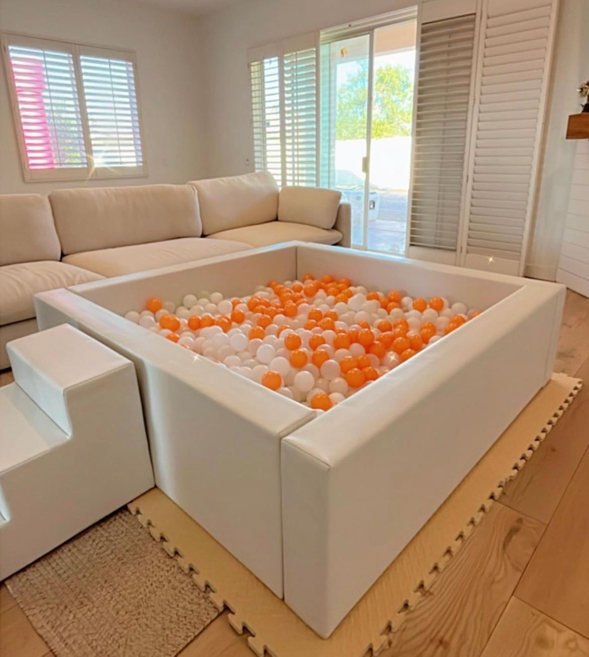 Modern living room with a white indoor ball pit filled with orange and white balls
