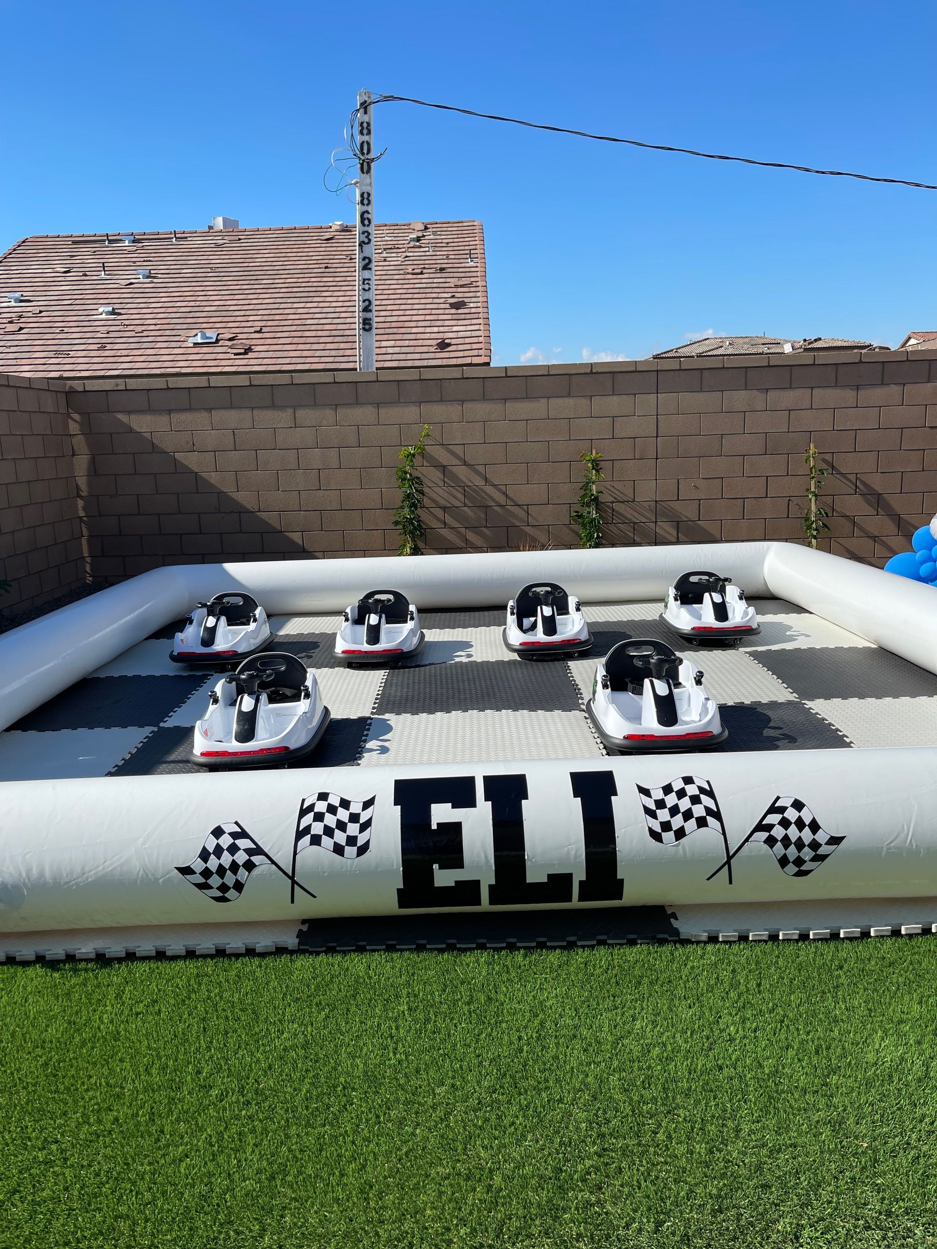 Two white foam drones arranged on a tabletop with ELI logo, outdoors on artificial grass against a block wall.