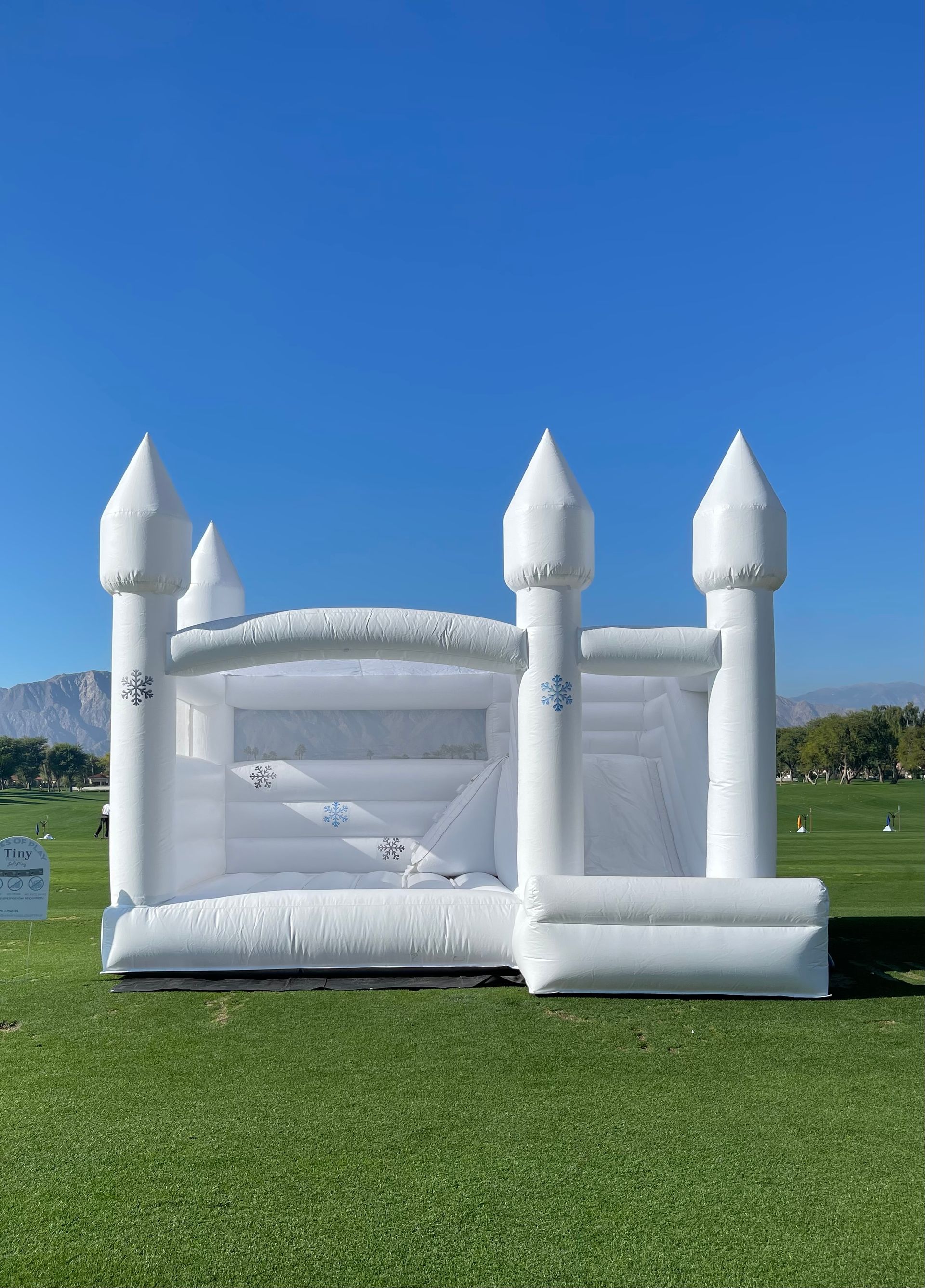 White inflatable castle on a grassy field under a clear blue sky