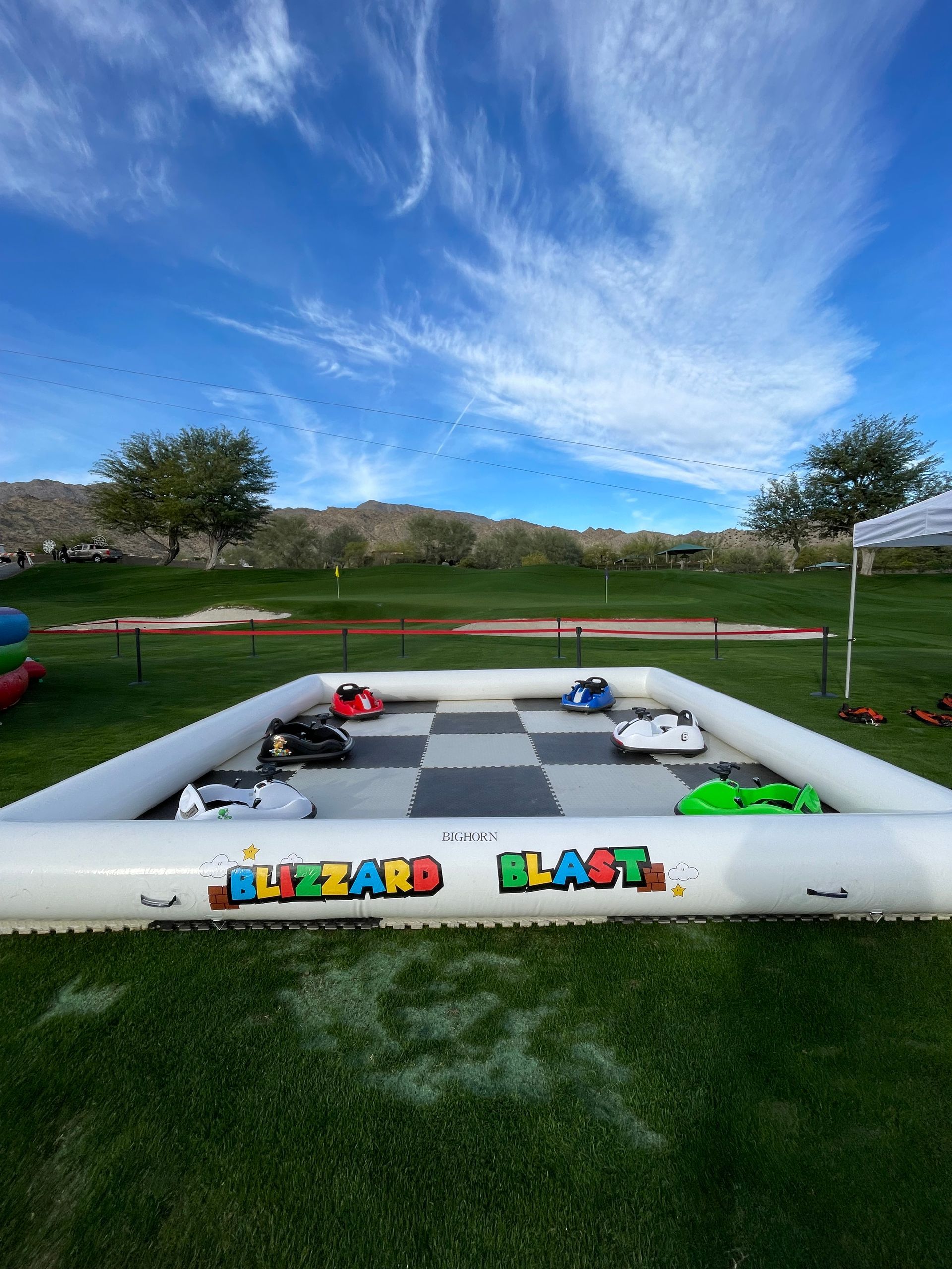 Inflatable toy race track with colorful cars on grass under a blue sky