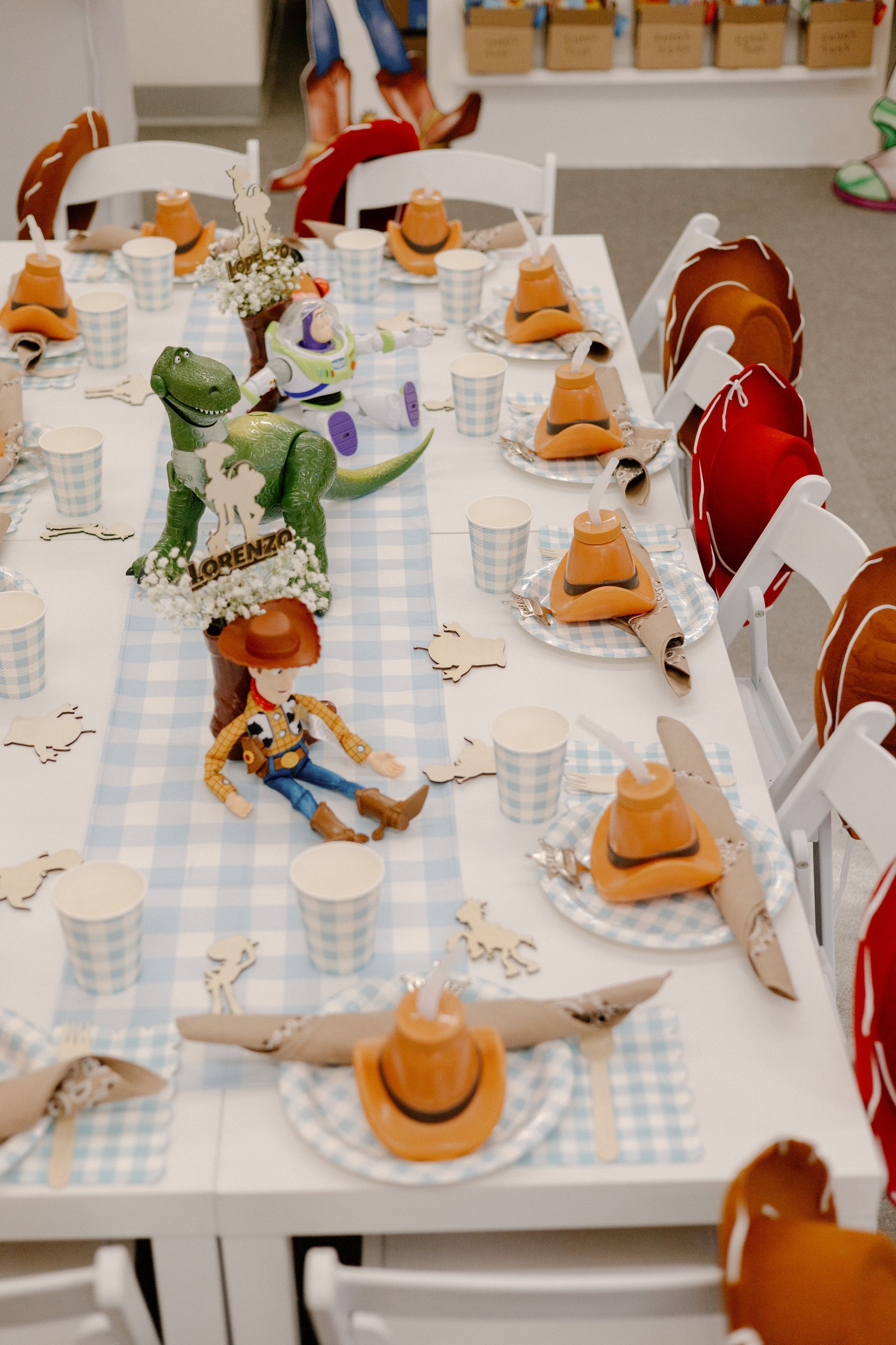 Miniature dining table with tiny figures, white chairs, and pastries on a blue checkered tablecloth