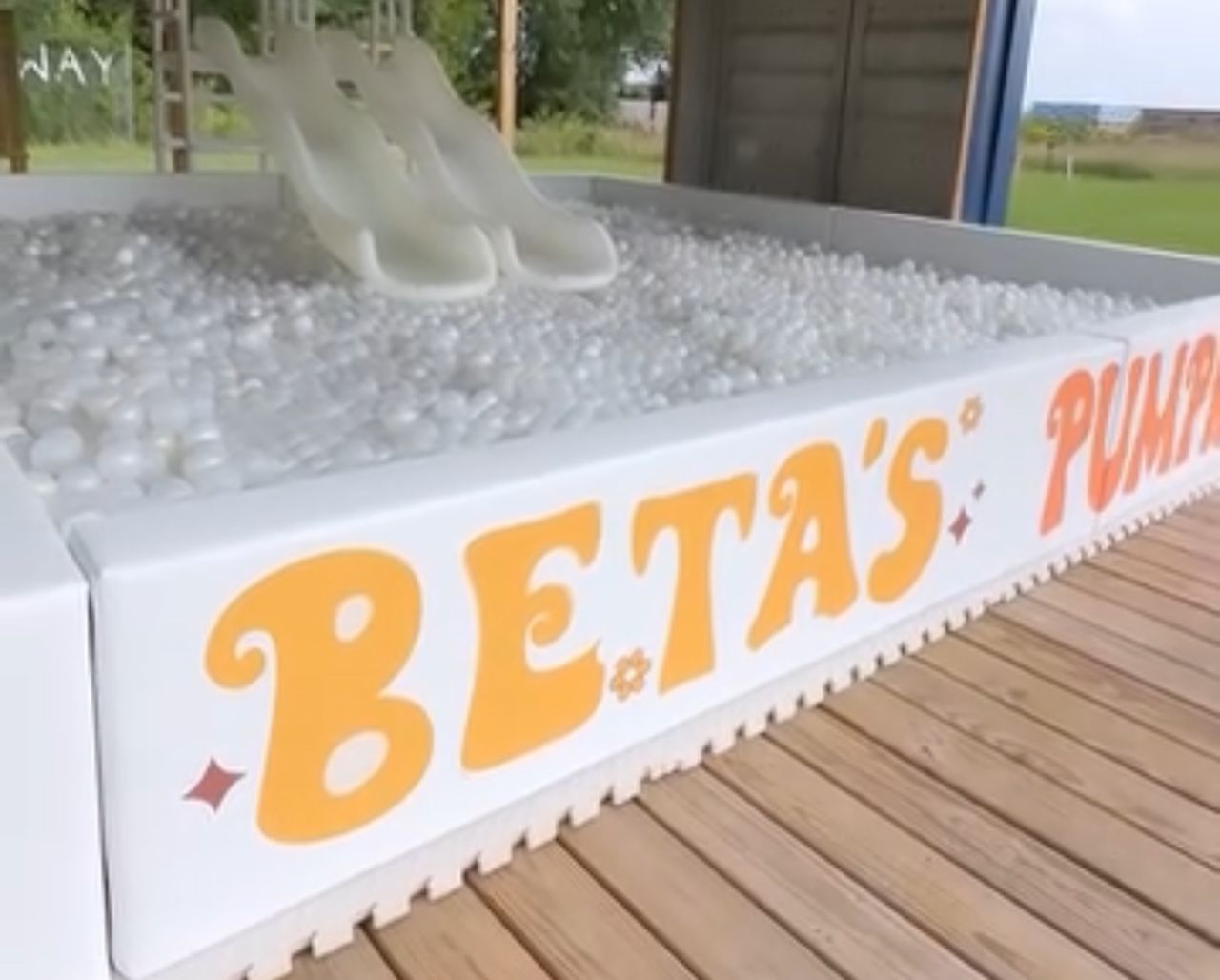 BETA’S PUMPS sign on a white display table filled with clear plastic balls near a wooden deck