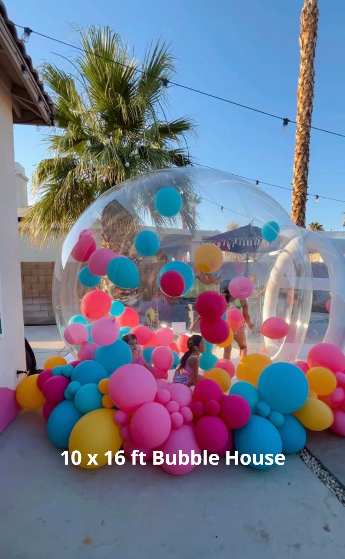 Transparent bubble house filled with colorful balloons outdoors in sunny courtyard