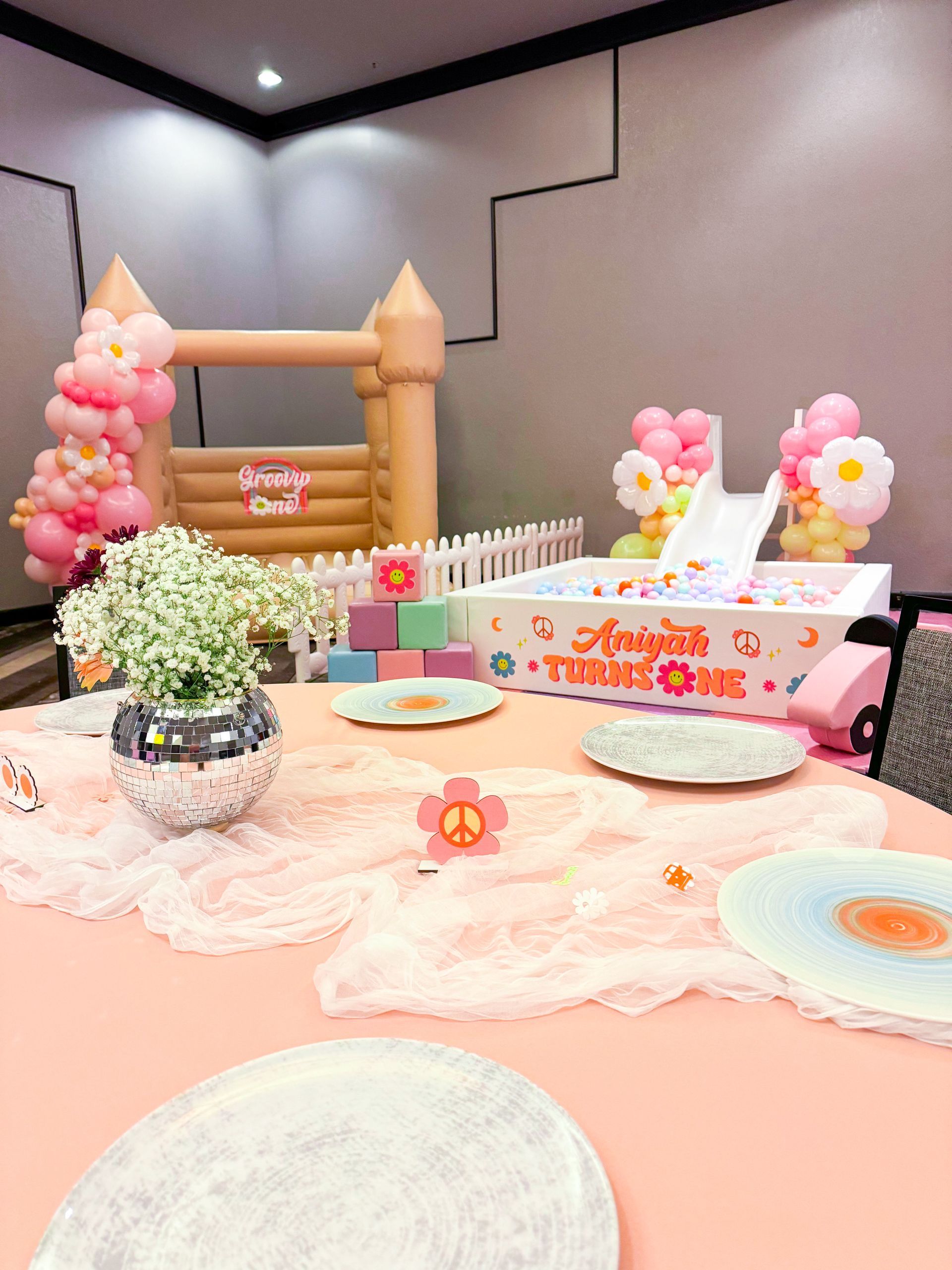 Pastel-themed dessert table with cakes, flowers, and balloons for a birthday party