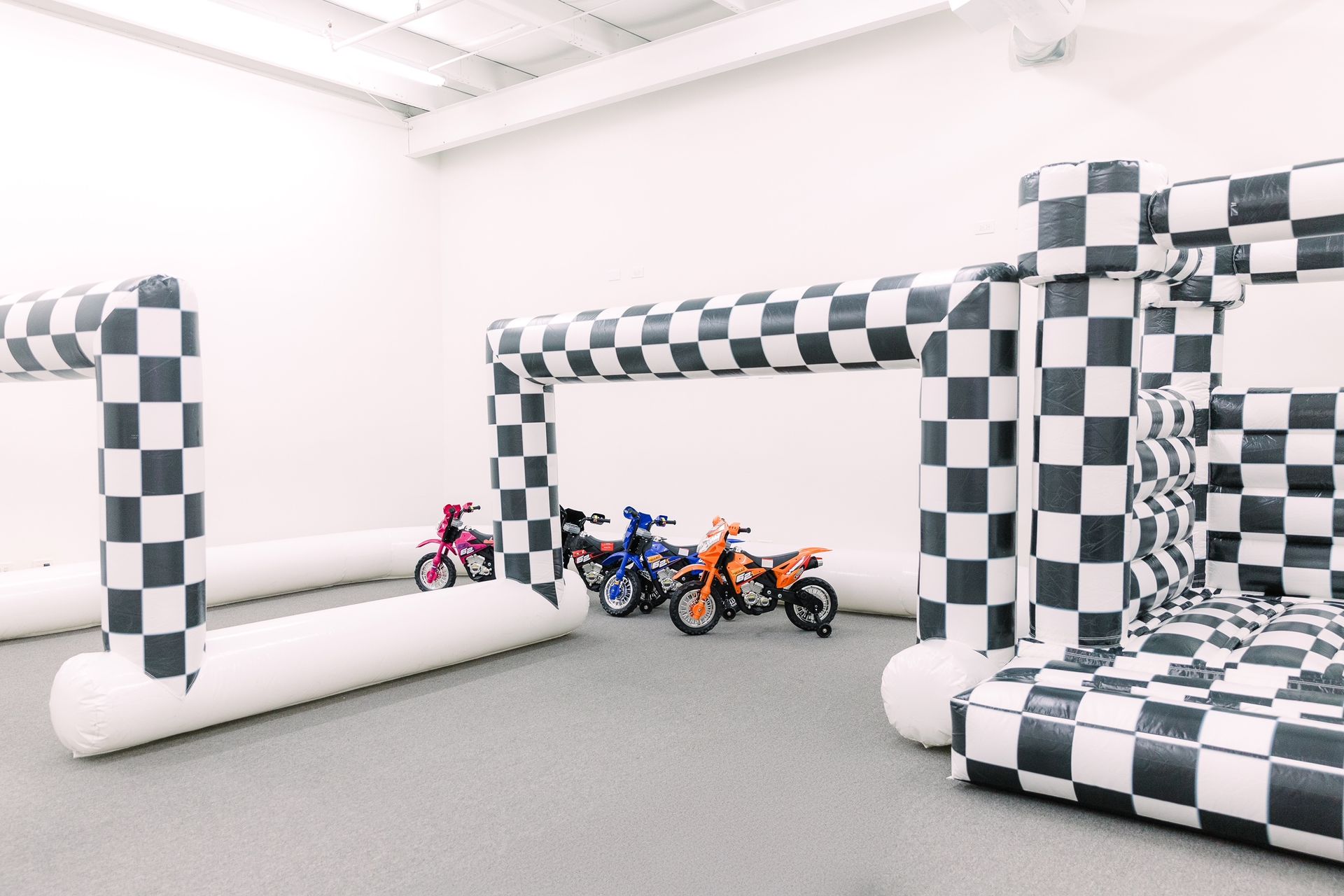 Checkered inflatable obstacle course with small motorbikes in a bright indoor room