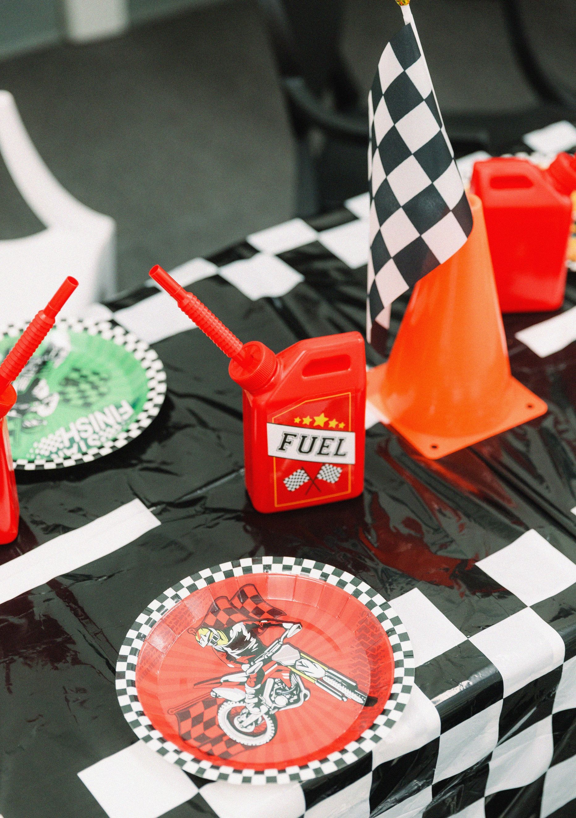 Checkered racing party table with red fuel can centerpiece, cones, and checkered flags