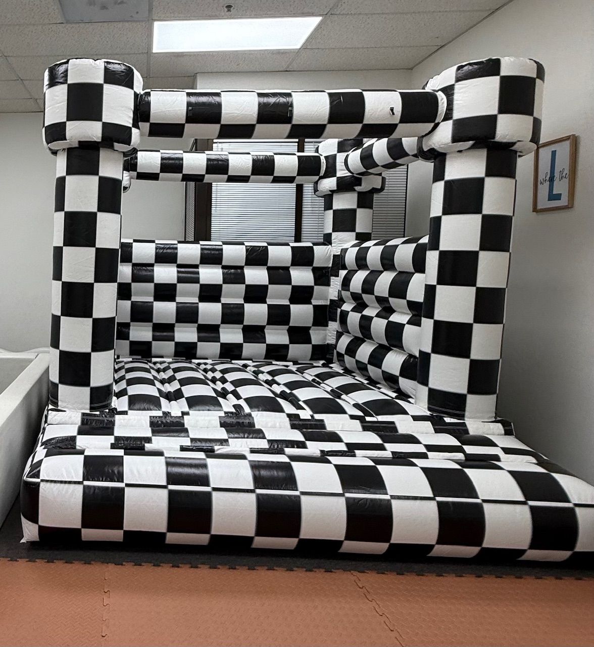 Black-and-white checkered inflatable tunnel obstacle in a hallway