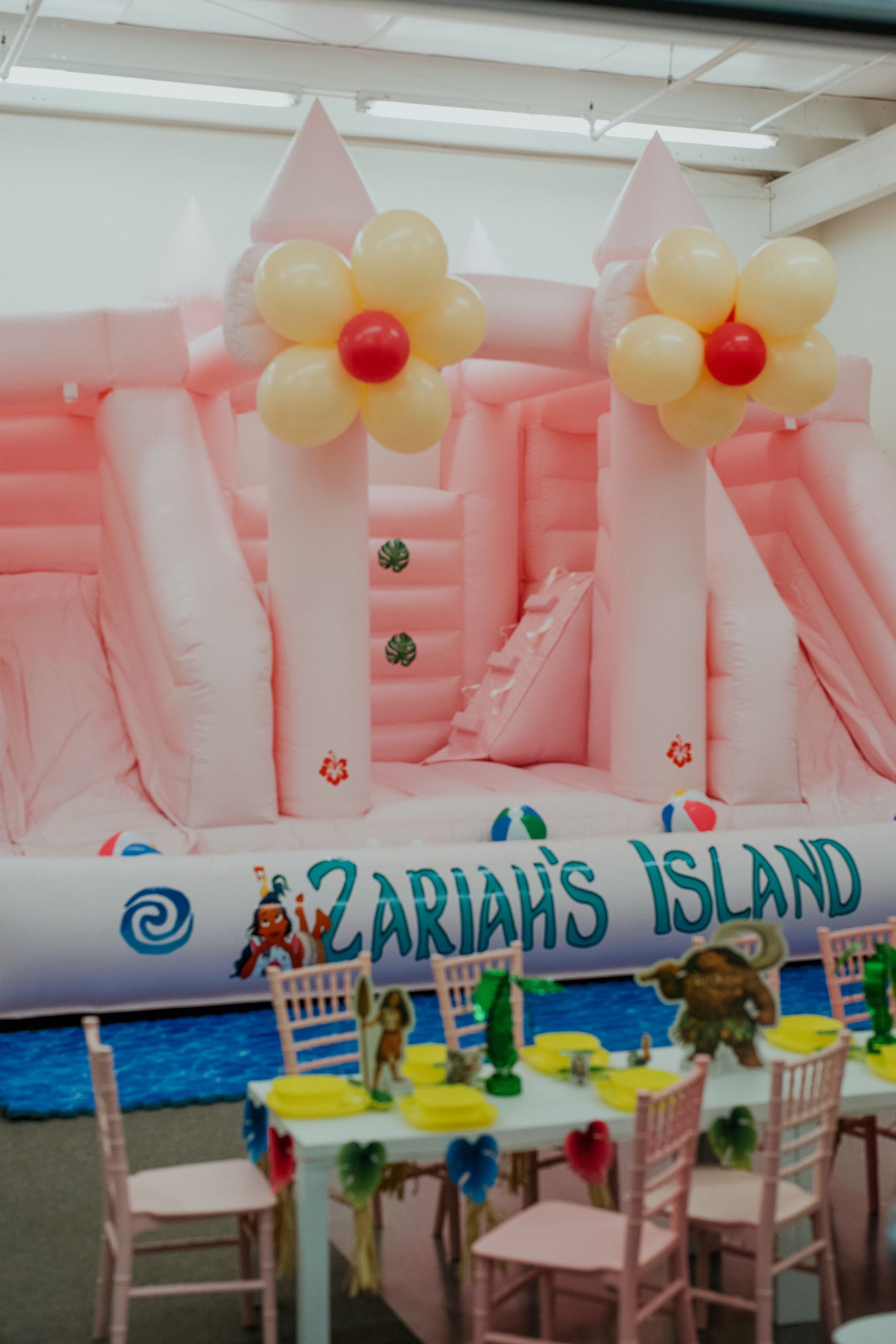 Pink balloon castle backdrop at Zariah’s Island party table with pastel decorations and chairs