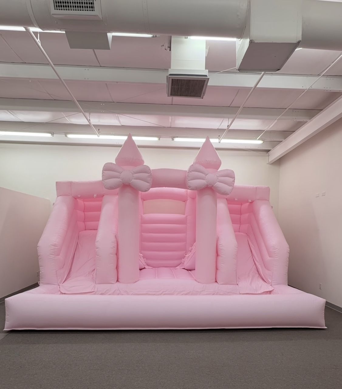 Pink inflatable castle bounce house indoors in an empty room