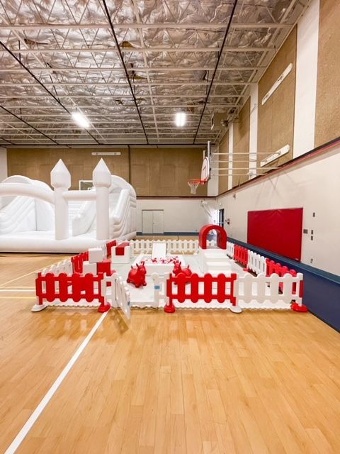 Inflatable white castle with red fence in an empty indoor gymnasium