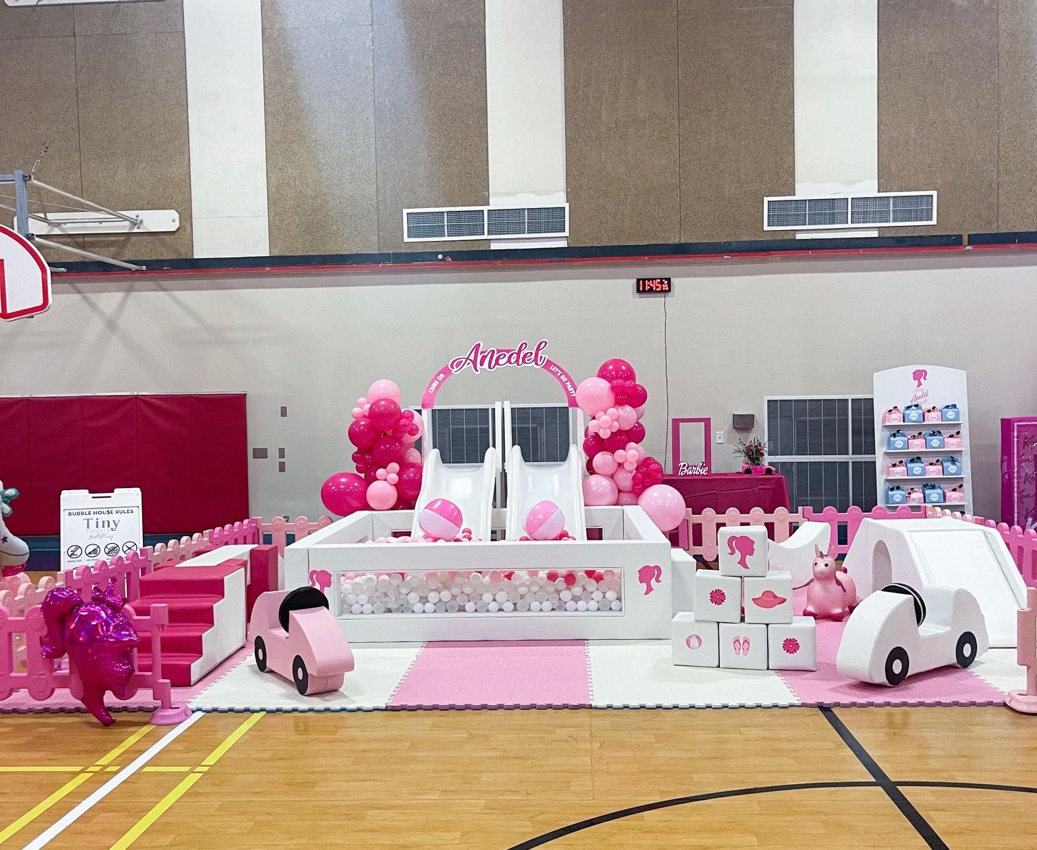Pink-and-white decorated gym display with balloons, tables, and stroller-themed props