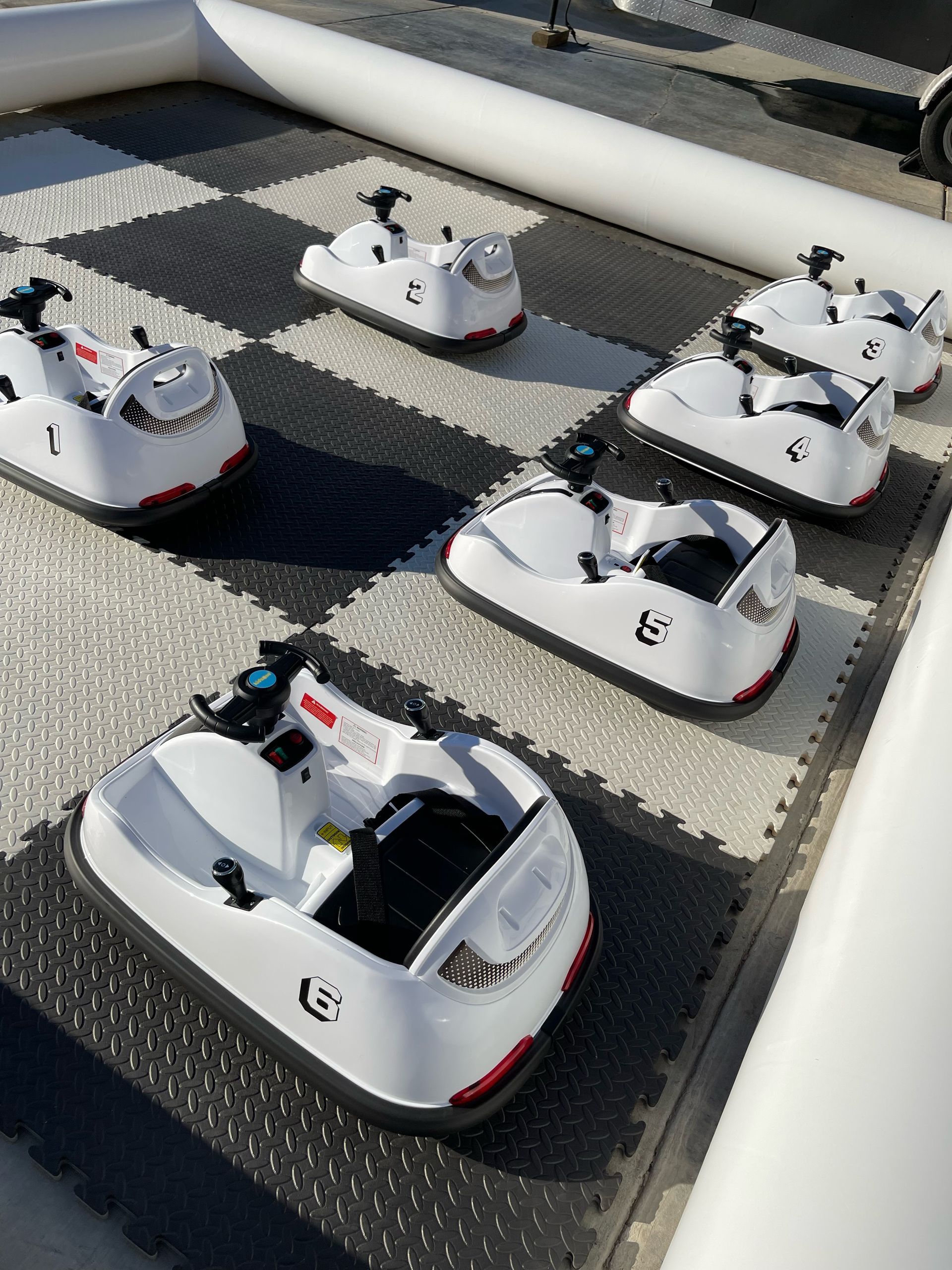 Several small white robot cars lined up on a paved course outdoors.