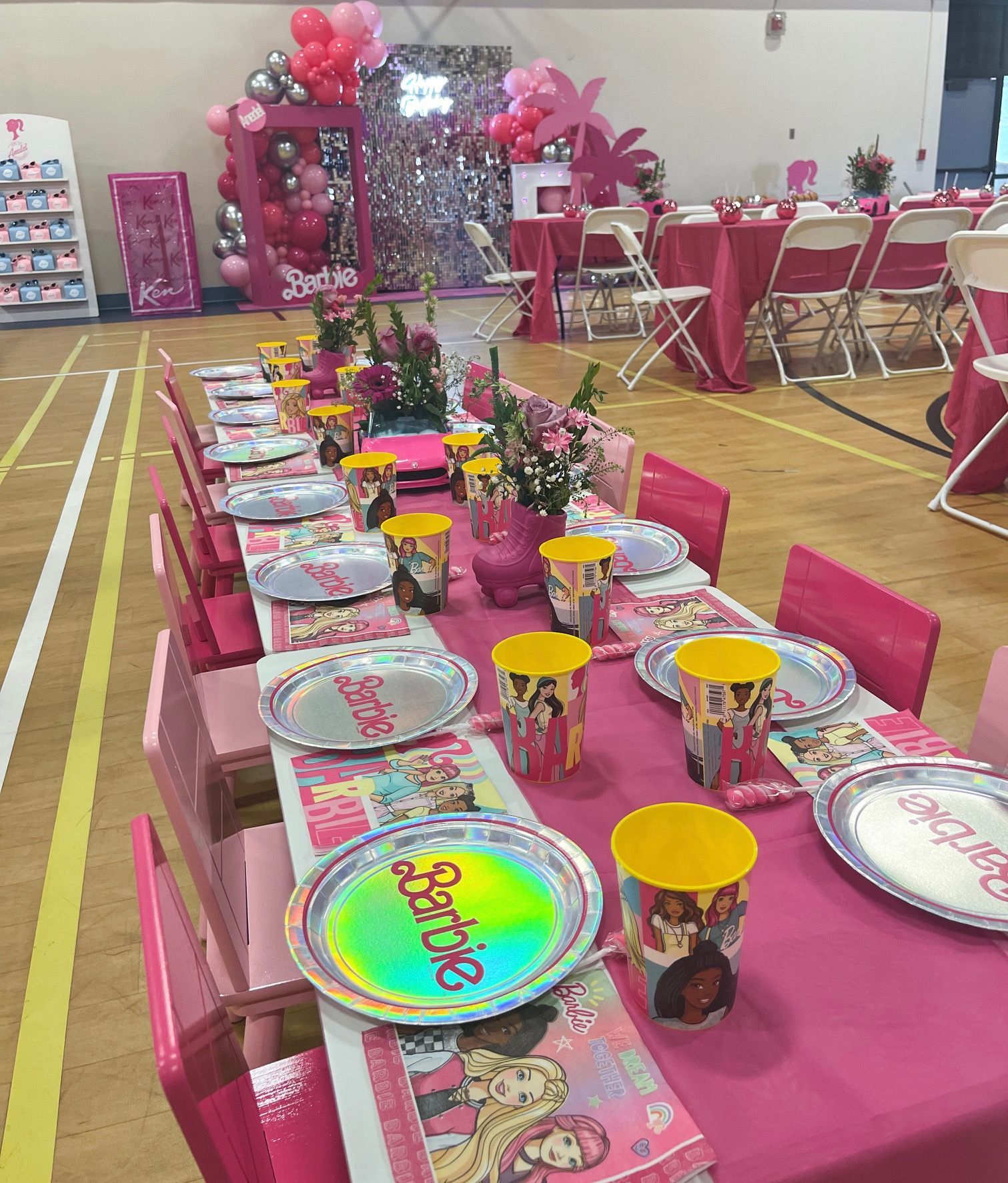 Pink-decorated party table set with plates, cups, and flowers in a hall