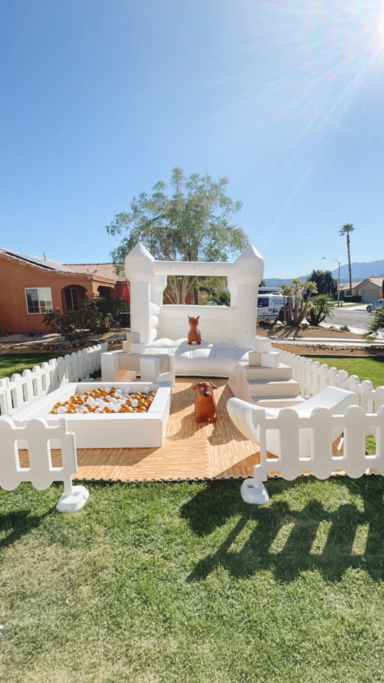 White wedding-style decorative garden setup with arch, benches, and orange aisle on a sunny lawn